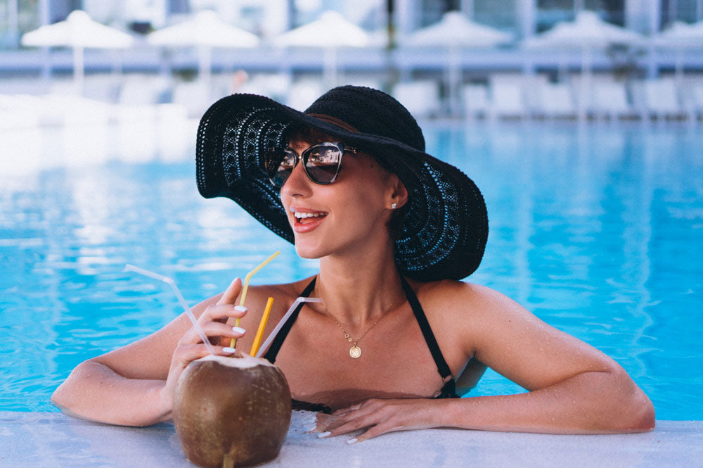 Woman in a Miami Beach hotel pool drinking a coconut cocktail