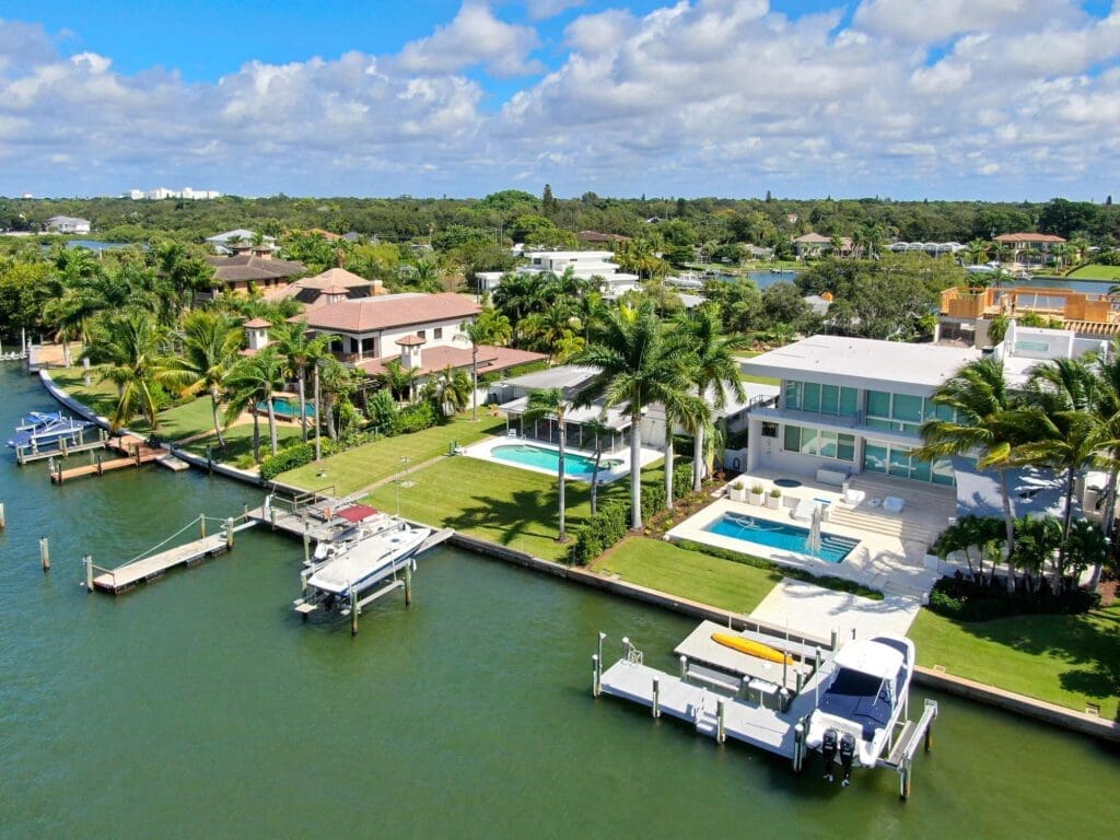 An aerial view of luxury waterfront villas in Bay Island, Sarasota, with private docks and boats on a sunny day.