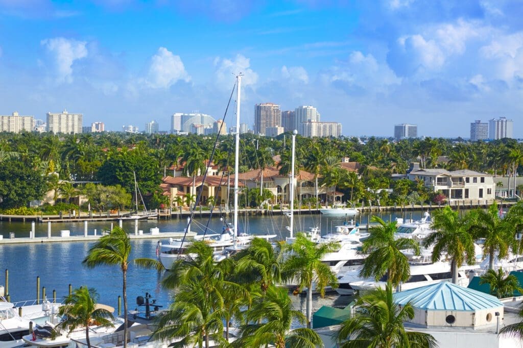 A view of the Stranahan River in Fort Lauderdale, with yachts docked along the bank, and a skyline of buildings in the background.