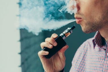 A man takes a deep breath and exhales a cloud of vapor from his electronic cigarette