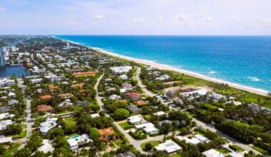 Aerial drone footage highlighting a beachside residential area in South Florida, featuring stunning turquoise waters set against a bright blue sky