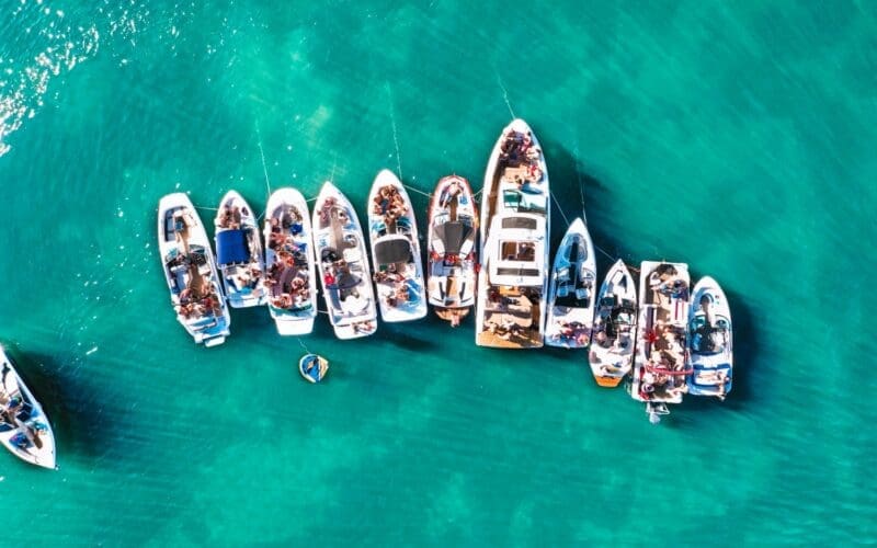 Aerial drone view capturing various sizes of boats anchored near the beach of an island in Biscayne Bay