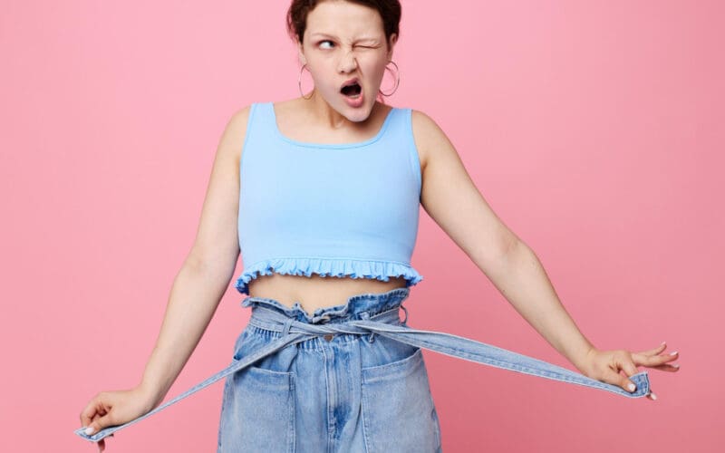 Close-up of a funny girl making a grimace, showcasing her emotions about weight loss while posing with earrings—authentic lifestyle moment.