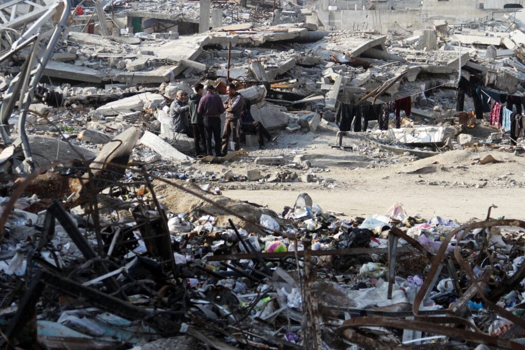 Palestinians stand among the rubble of houses destroyed in previous Israeli strikes, amid ceasefire negotiations with Israel, in Gaza City
