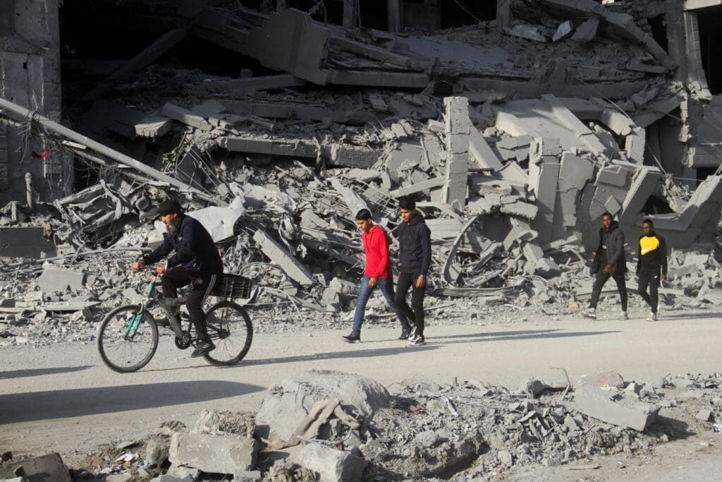 Palestinians walk among the rubble of houses destroyed in previous Israeli strikes, amid ceasefire negotiations with Israel, in Gaza City