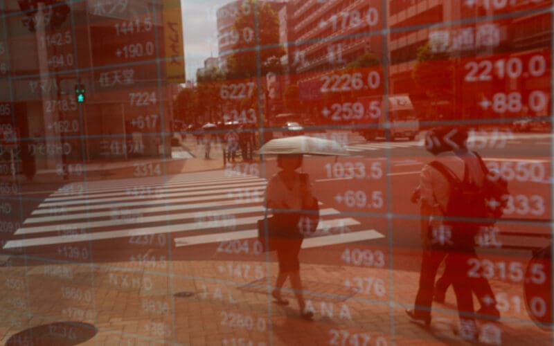 A woman is reflected on an electronic stock quotation board outside a brokerage in Tokyo
