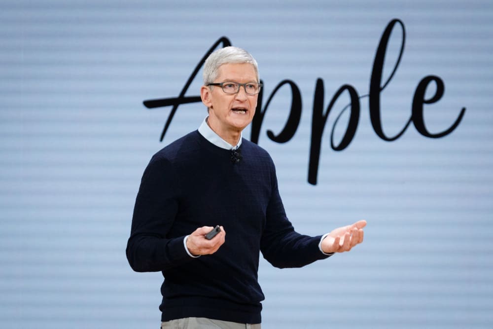 Apple CEO Tim Cook speaks on stage with a microphone and a remote in his hands