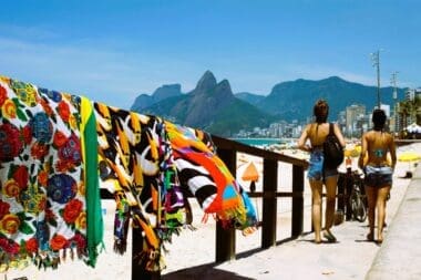 Two women stroll toward Ipanema Beach in Rio de Janeiro on a sunny day