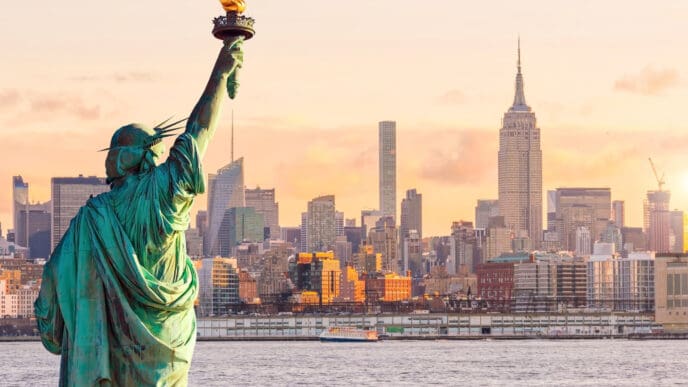 Statue Liberty and New York city skyline at sunset, in United States.