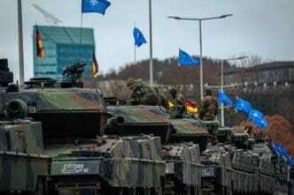 Vilnius, Lithuania - 11 25 2023: A column of German armored vehicles during NATO parade. High-quality photo. Waving NATO flags.