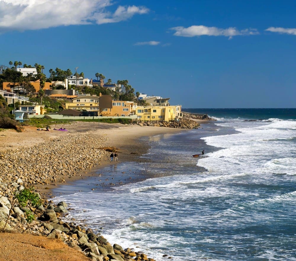 A beautiful vista of County Line Beach in Malibu, with surfers, waves and beautiful houses in the background