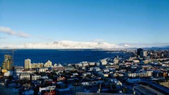 Aerial shot of the coastal city of Reykjavik with snow covered mountains