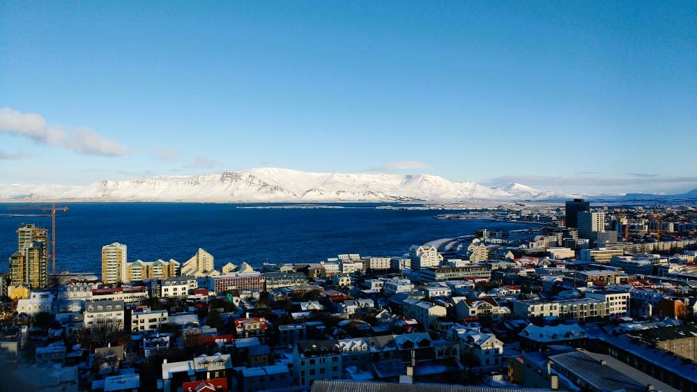 Aerial shot of the coastal city of Reykjavik with snow covered mountains