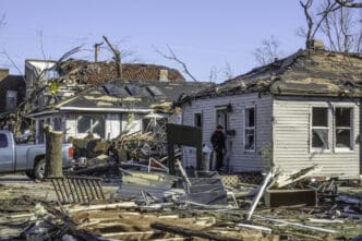 NAPLATE, ILLINOISUSA - MARCH 3, 2017. A young woman enters a small house severely damaged by an EF-3 tornado that devastated this small town. By Shutterstock.com - Ken Schulze