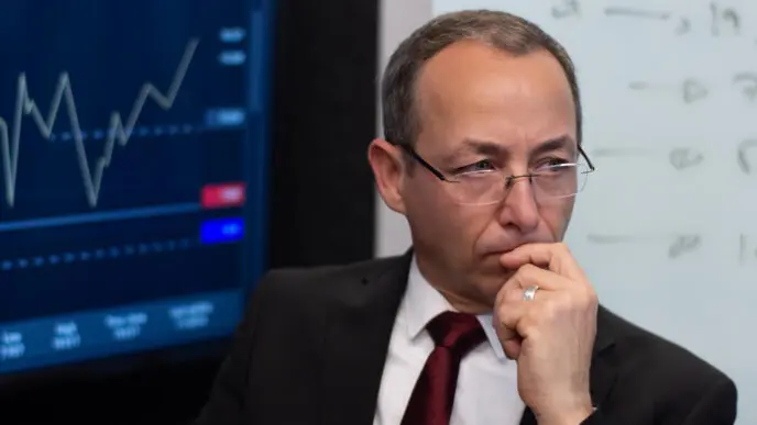 Portrait of a serious and thoughtful financial expert in his office, reflecting a hint of uncertainty