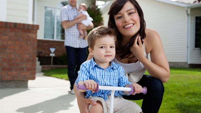 Portrait of happy family with house in background. By Shutterstock.com - Tyler Olson