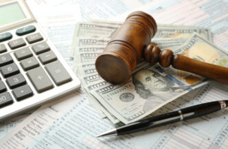 Judge's gavel and dollar banknotes on income tax form background.