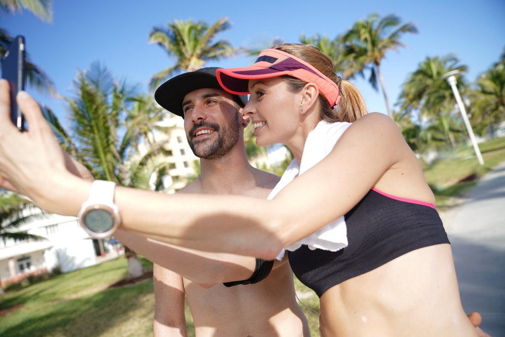A smiling man and woman take a selfie with a phone on a sunny day in Miami