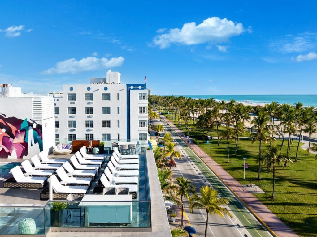 An aerial view of a rooftop with lounge chairs and the Park Central Hotel overlooking Ocean Drive in Miami Beach