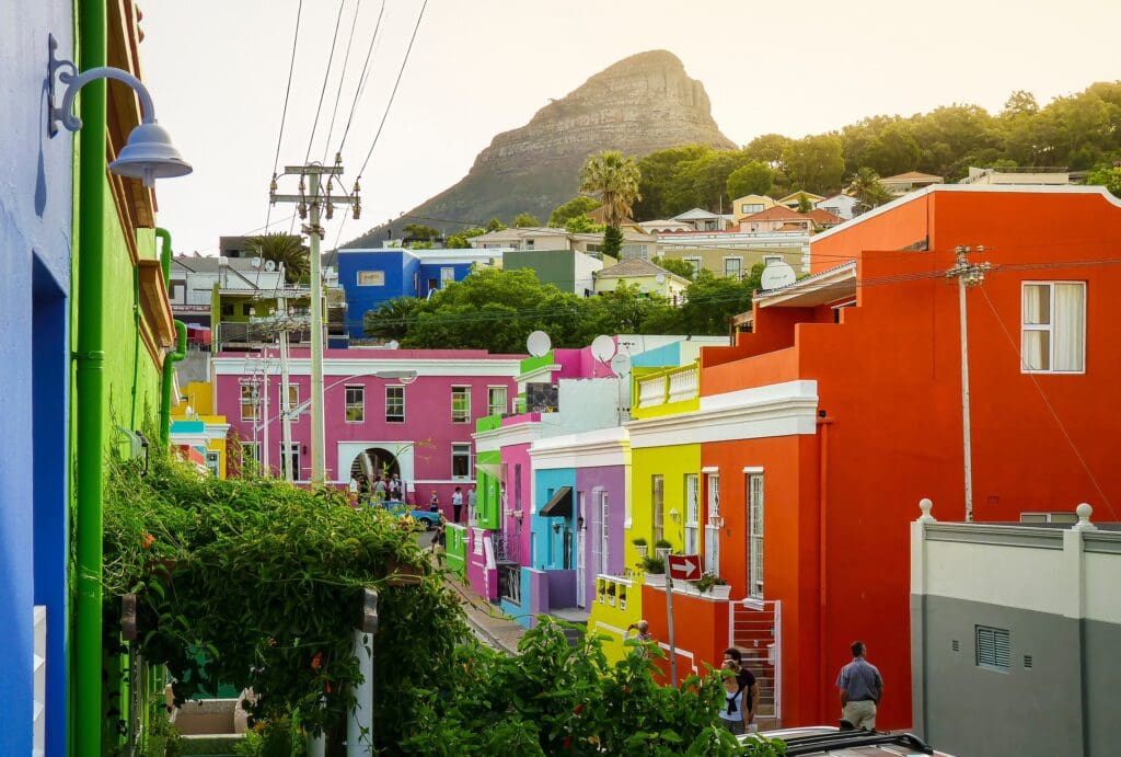Steep street lined with brightly colored houses in Bo-Kaap, Cape Town, with the prominent Lion's Head mountain in the background.