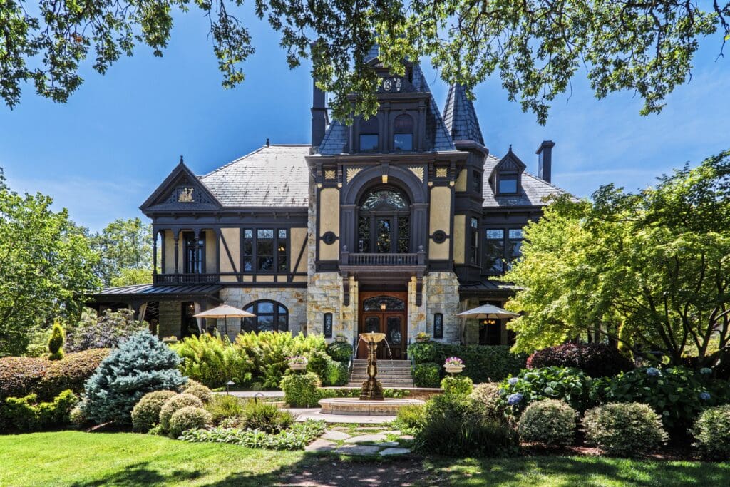 Front view of the historic Rhine House at Beringer Vineyards, a stately mansion with a turret and elaborate Victorian architecture, framed by lush gardens.