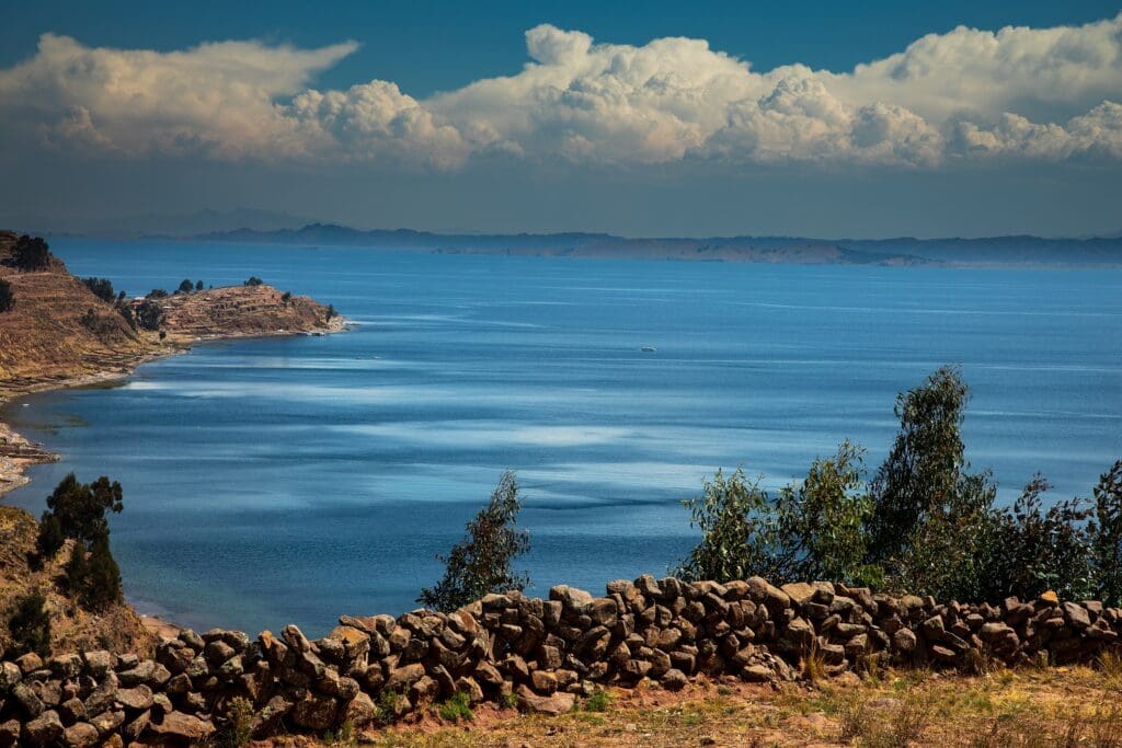 A high-angle view of the deep blue Lake Titicaca, with a stone wall in the foreground.