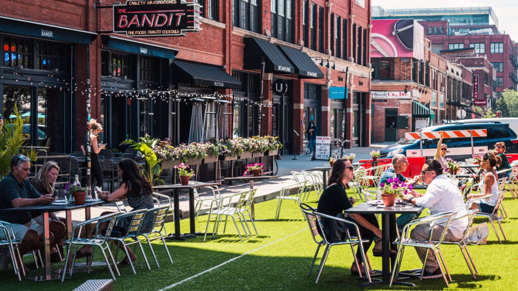 People dining outdoors on an artificial turf patio in front of "The Bandit" restaurant.