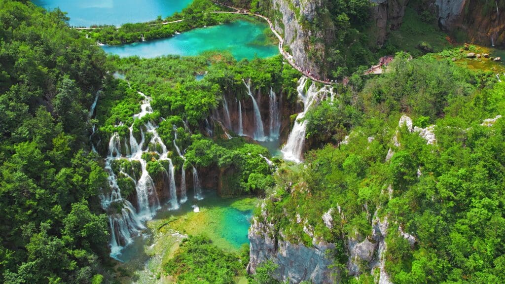 An aerial view of cascading waterfalls and turquoise lakes in Plitvice Lakes National Park.