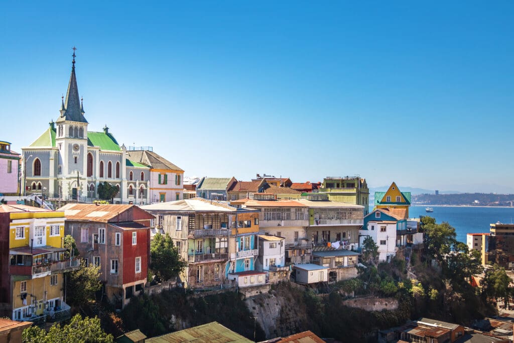 The colorful, dense hillside houses and prominent Lutheran Church spire of Valparaiso, Chile, overlooking the Pacific Ocean